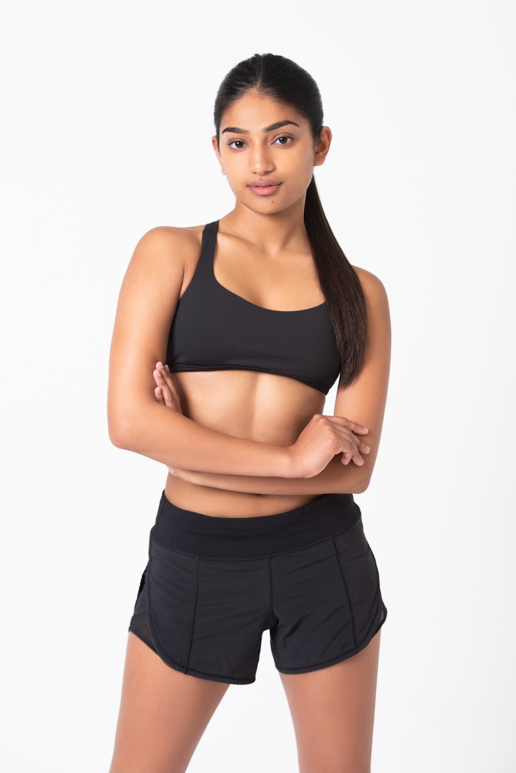 Mahika Valluri, studio portrait in black athletic wear, arms crossed