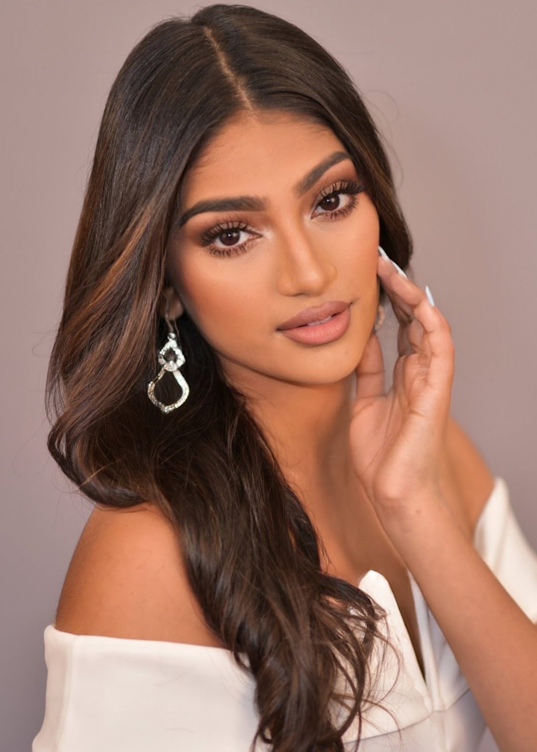 Beauty headshot of Mahika Valluri in a white off-shoulder top and silver earrings