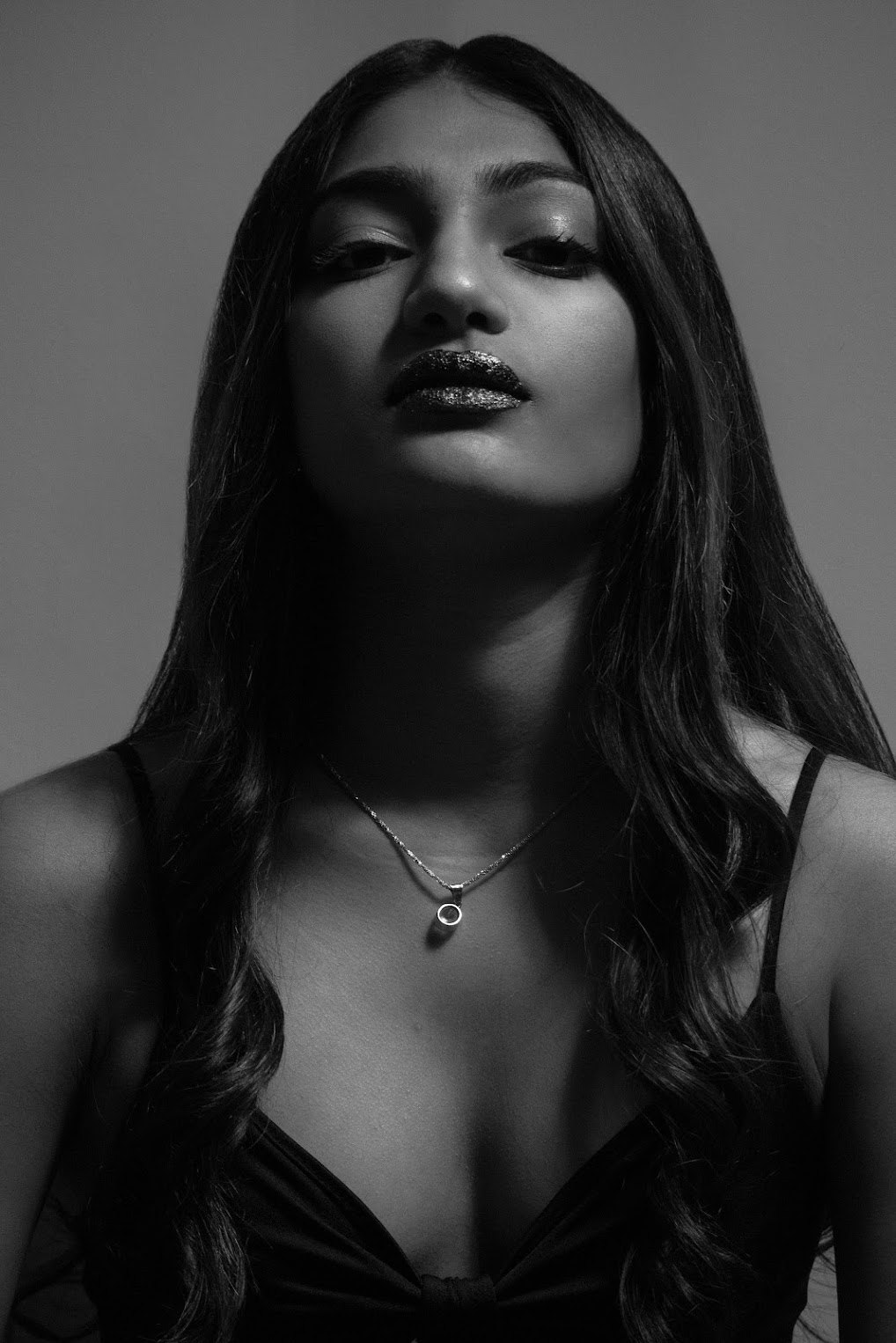 Editorial black-and-white photograph of Mahika Valluri seated in a black dress