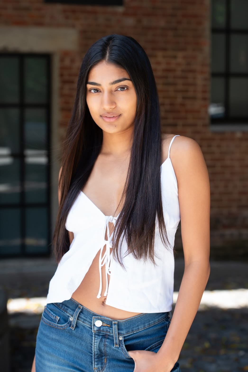 Mahika Valluri acting headshot, three-quarter portrait against brick