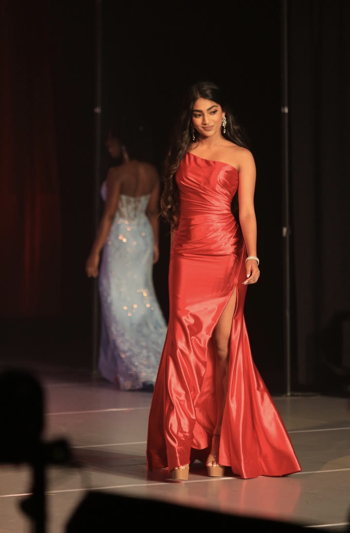 Mahika Valluri walking the stage in a red one-shoulder gown